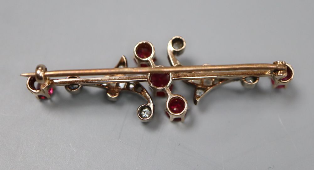 A yellow and white metal, ruby, diamond and seed pearl scrolling bar brooch (pearl missing), 46mm, gross 5.1 grams.